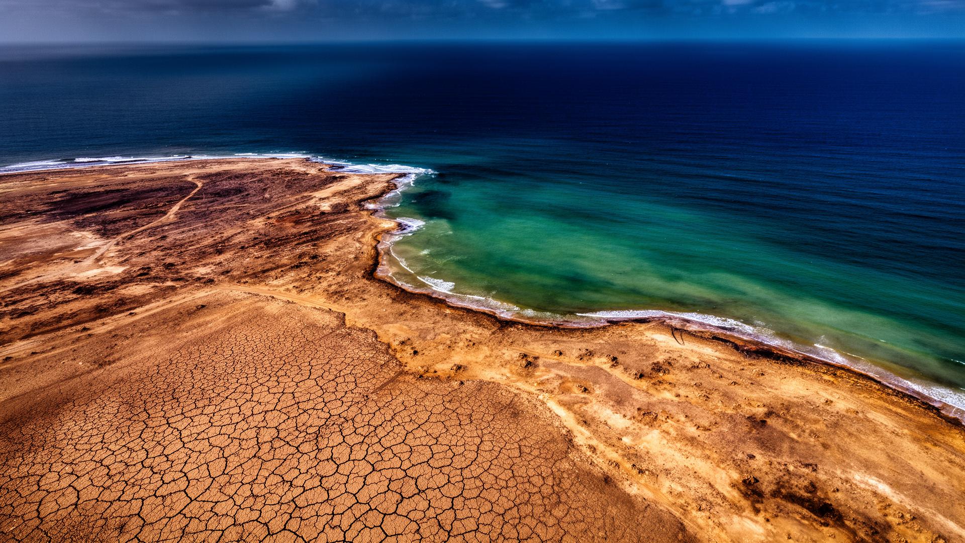Aerial view of degraded arid coastal land meeting deep blue ocean